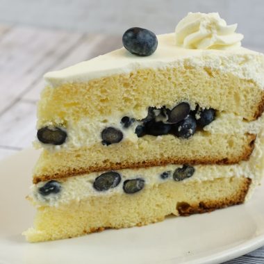 savor the classic flavor of a traditional lemon blueberry cake slice at Mia's Bakery.