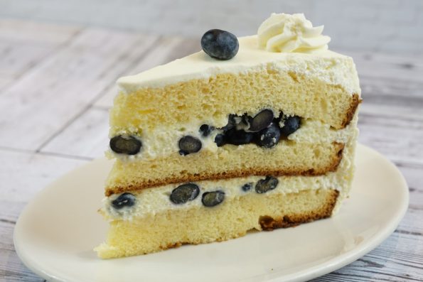 savor the classic flavor of a traditional lemon blueberry cake slice at Mia's Bakery.