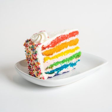 savor the classic flavor of a traditional rainbow cake slice at Mia's Bakery.
