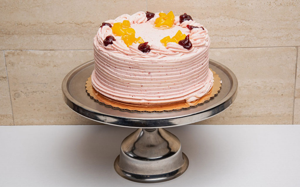 Peach raspberry layer cake with pink frosting and fresh fruit topping as creative 4th of July dessert ideas