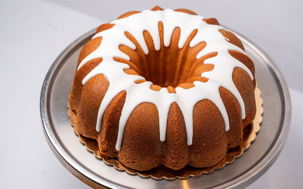 Spring dessert ideas lemon bundt cake with white glaze drizzle on a professional cake stand