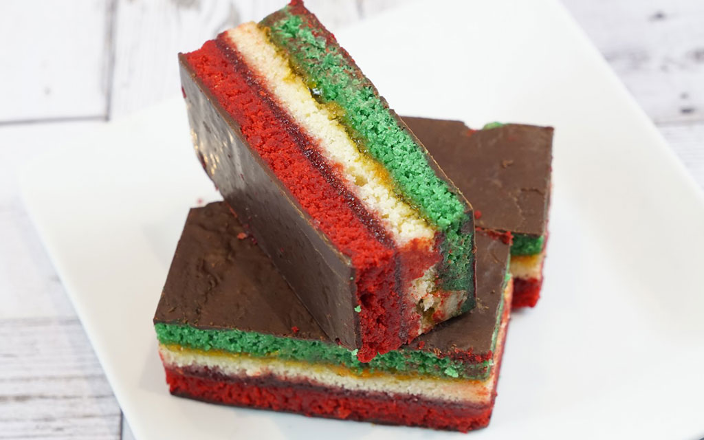 Italian rainbow cookie bars with red, yellow, and green almond layers covered in chocolate, festive valentines dessert ideas for parties