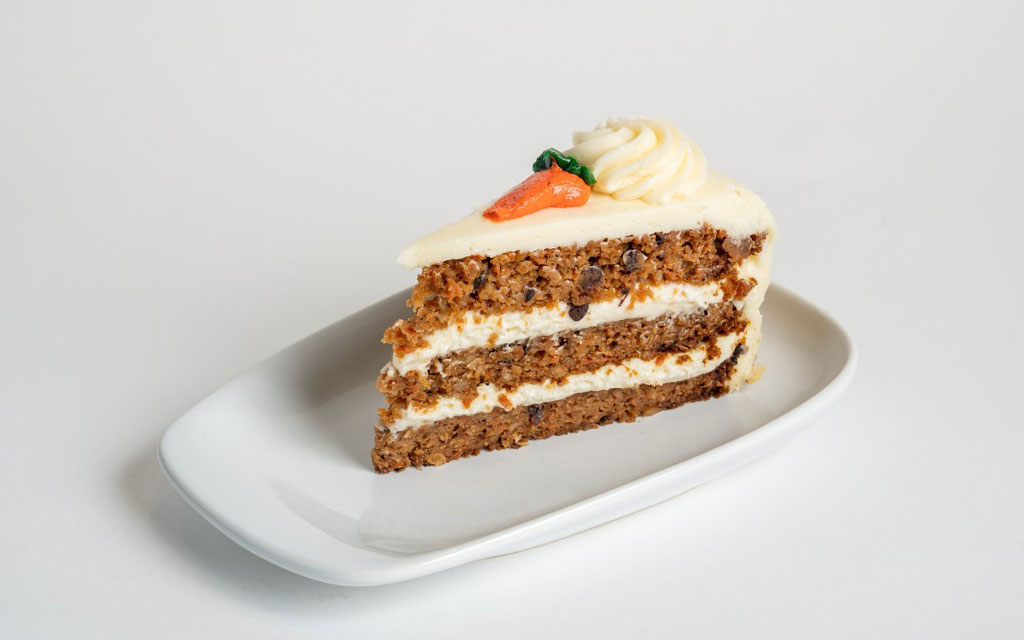 Best Easter desserts carrot cake slice with cream cheese frosting and decorative carrot topper