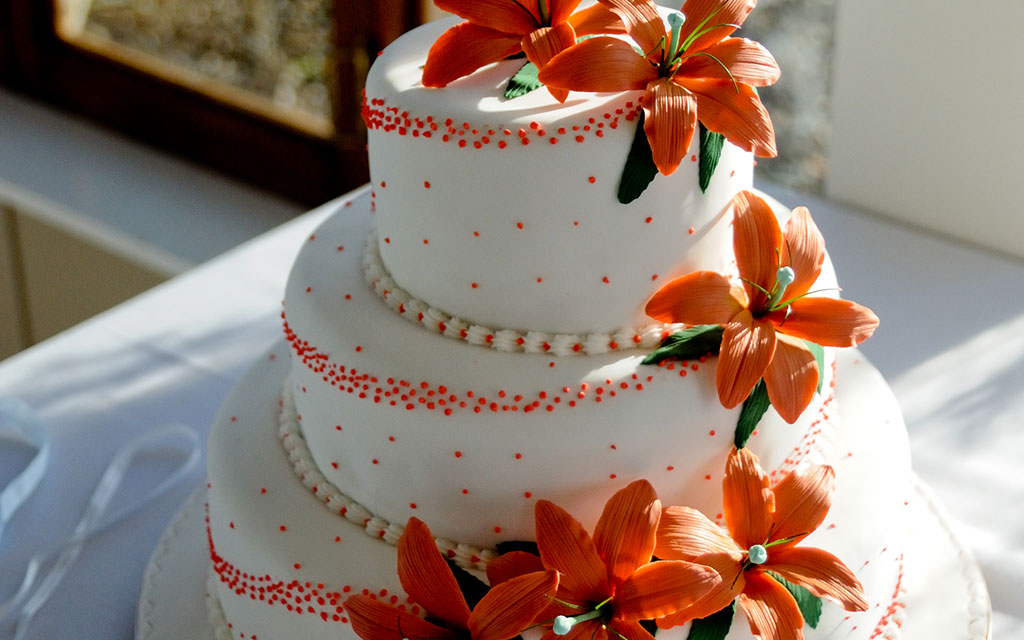 Carrot cake wedding cake with cream cheese frosting and orange lilies for fall wedding celebration