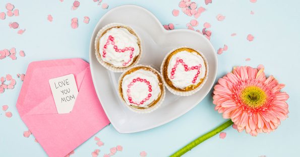 Mother's Day dessert ideas with three decorated cakes spelling MOM on a heart-shaped plate
