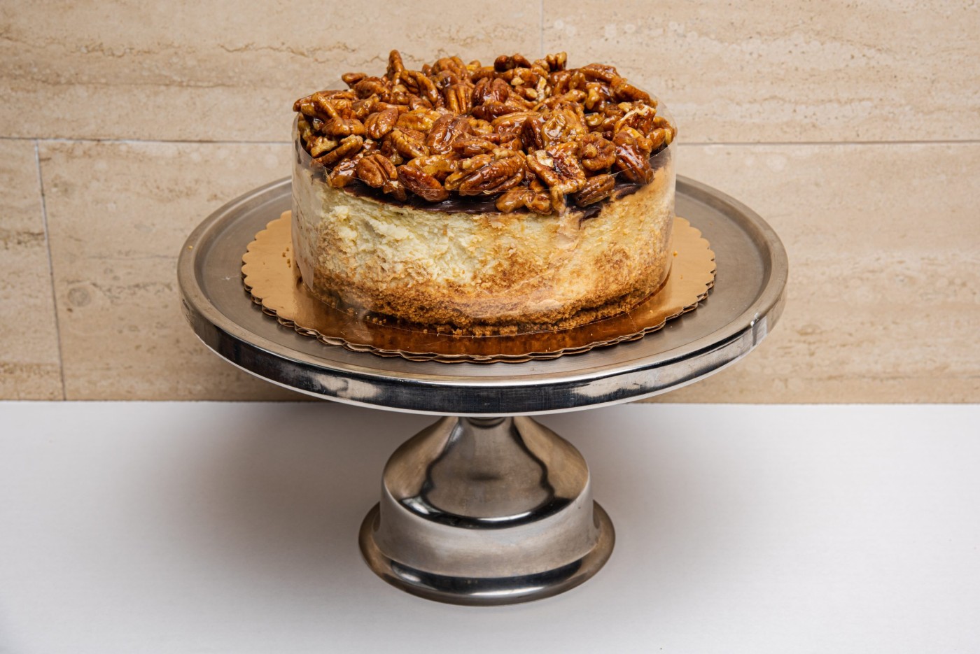 Pecan praline cheesecake on silver cake stand, elegant fall dessert idea for celebrations