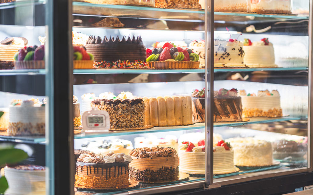 Seasonal desserts in professional bakery display case showing variety of cakes with different flavors and decorations