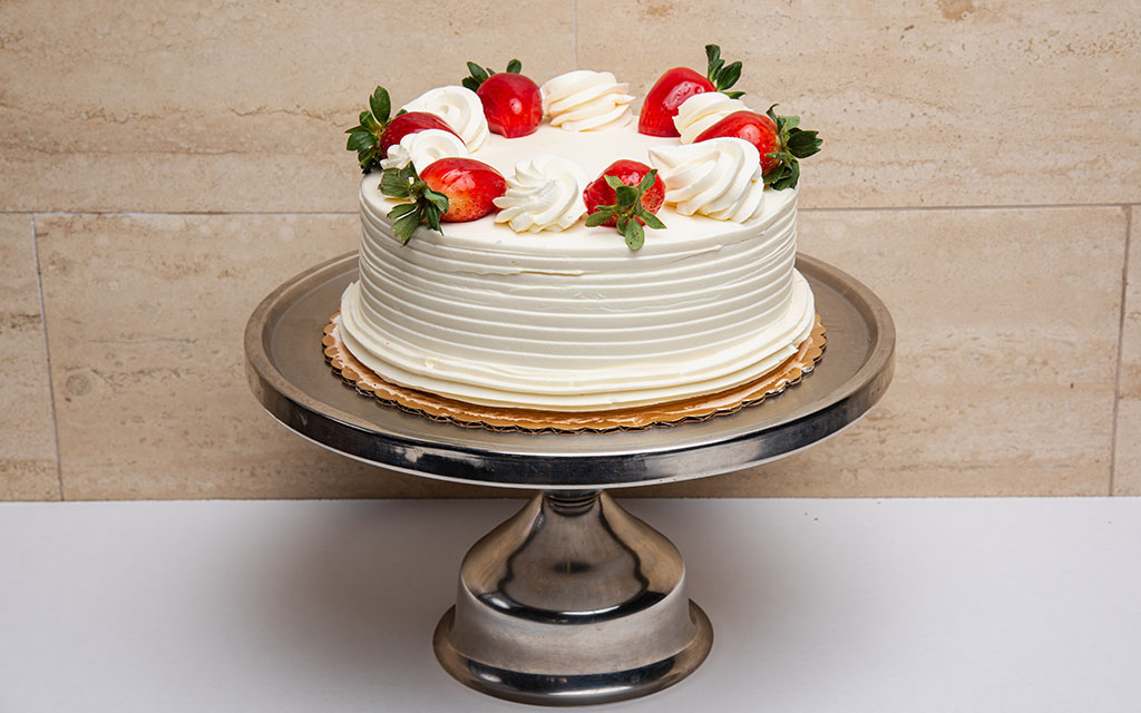 Seasonal desserts for spring featuring strawberry shortcake cake with fresh strawberries and whipped cream frosting on a cake stand