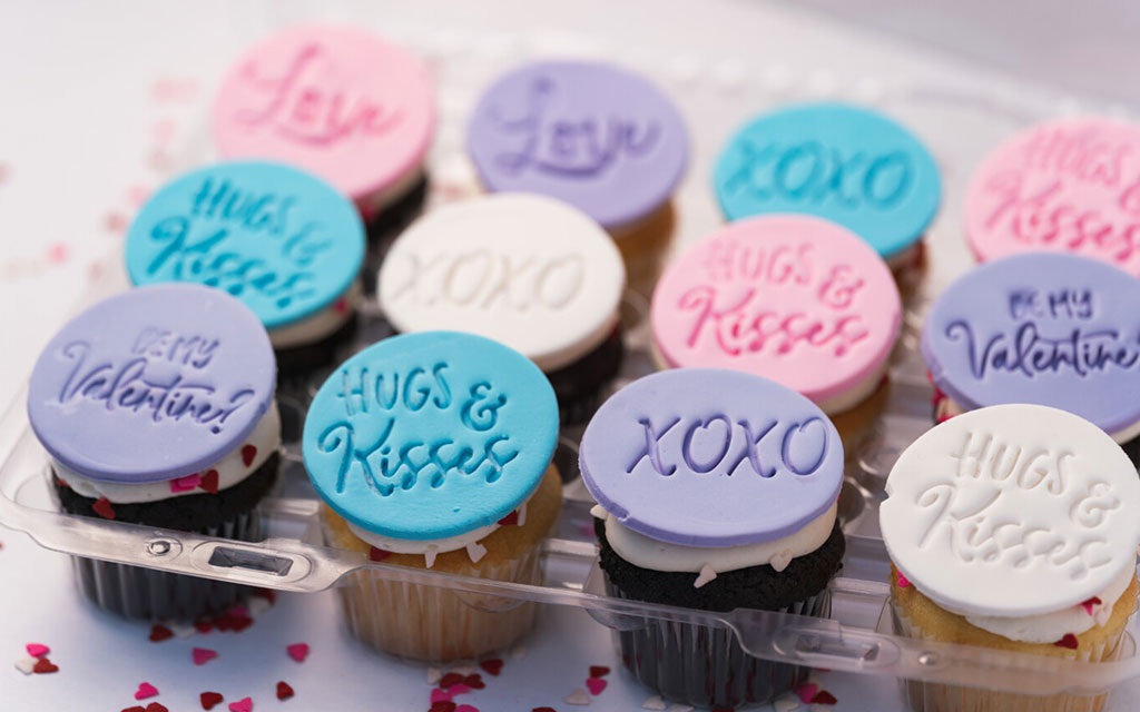 Seasonal desserts for Valentine's Day featuring cupcakes with pastel fondant toppers and romantic message decorations