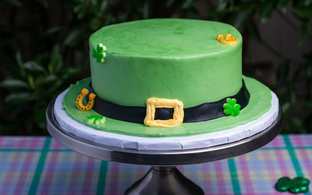 Green leprechaun hat cake with shamrocks and gold buckle as creative St Patrick's Day dessert ideas