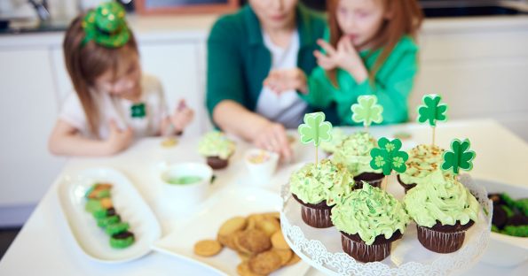 Family enjoying St Patrick's Day dessert ideas with green frosted cupcakes topped with shamrock decorations