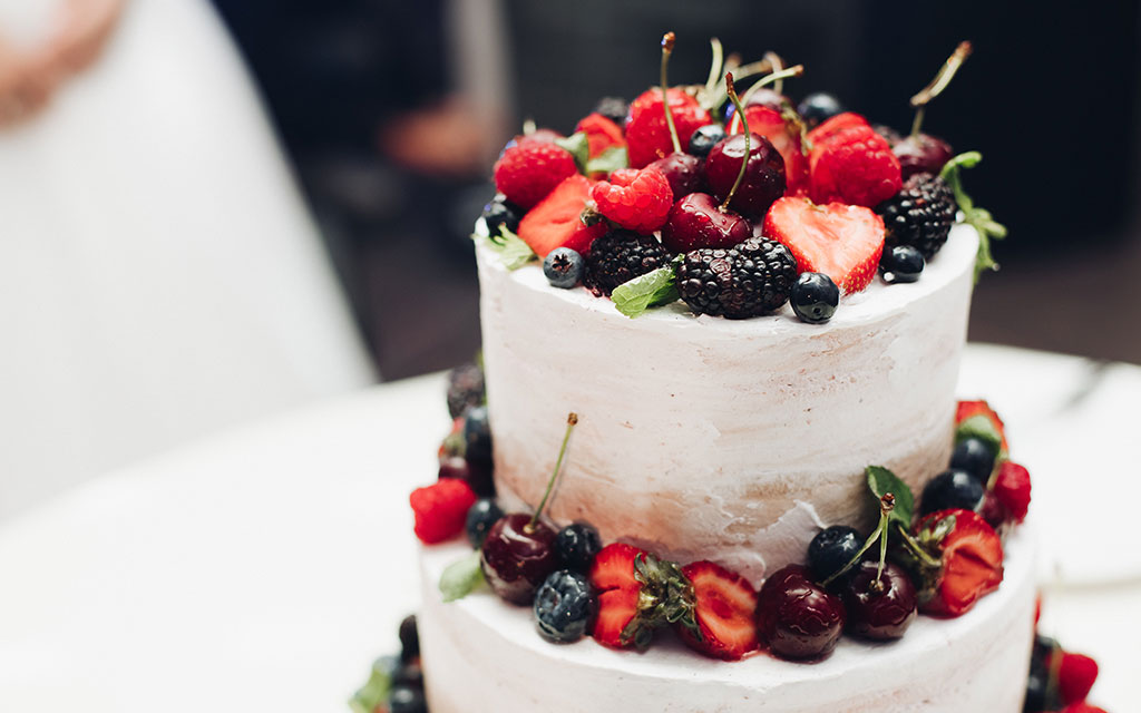Summer wedding cake with textured buttercream topped with fresh strawberries, cherries, blackberries, and blueberries