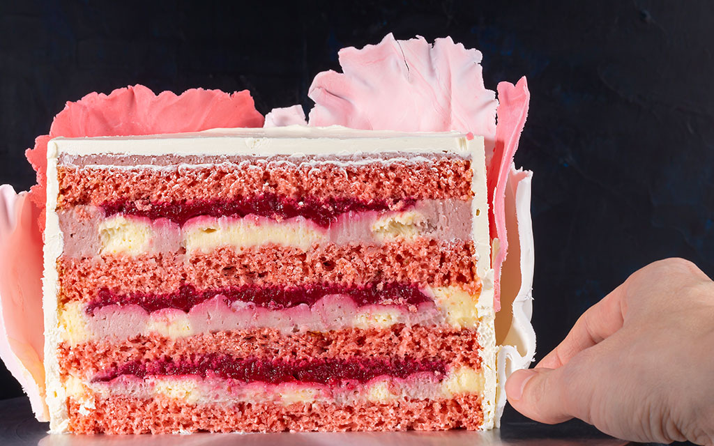 Summer wedding cake slice showing red velvet layers with berry compote filling and vanilla cream in cross-section view