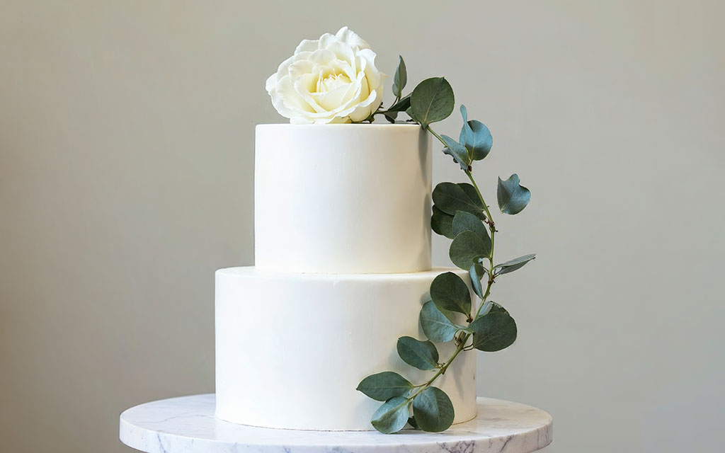Classic vanilla wedding cake with smooth buttercream frosting and eucalyptus for modern minimalist wedding