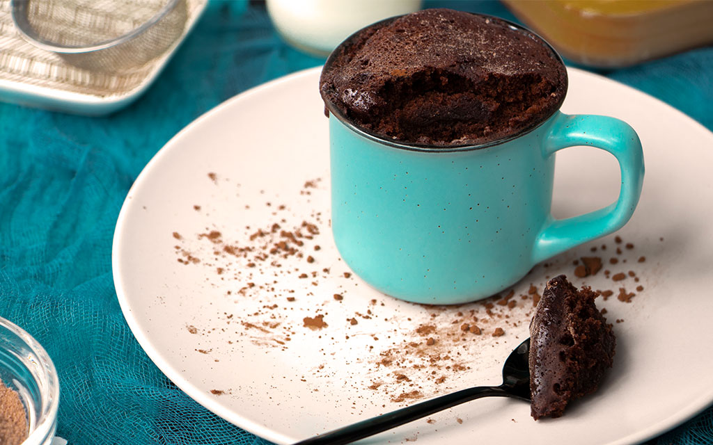 Chocolate mug cake in a turquoise mug dusted with cocoa powder, a quick winter dessert idea ready in minutes