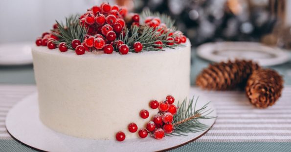 Winter wedding cake with sugared cranberries and evergreen sprigs on white buttercream