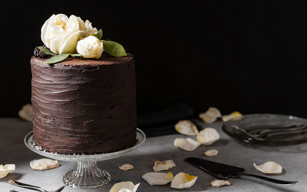 Chocolate winter wedding cake with textured buttercream and white flowers on crystal stand