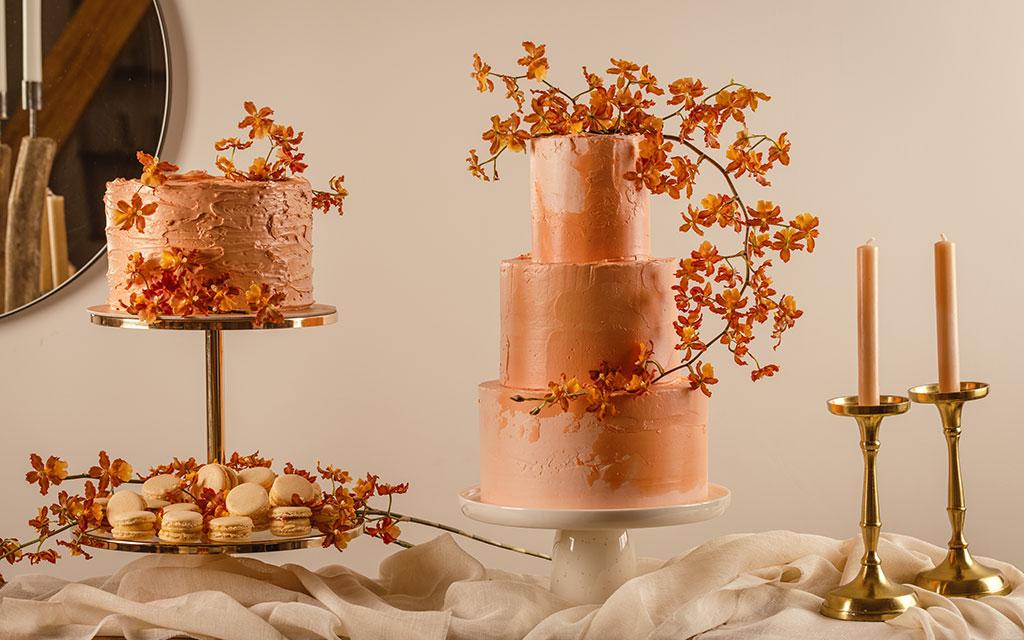 Burnt orange fall wedding cake with textured buttercream and autumn flowers on elegant dessert table