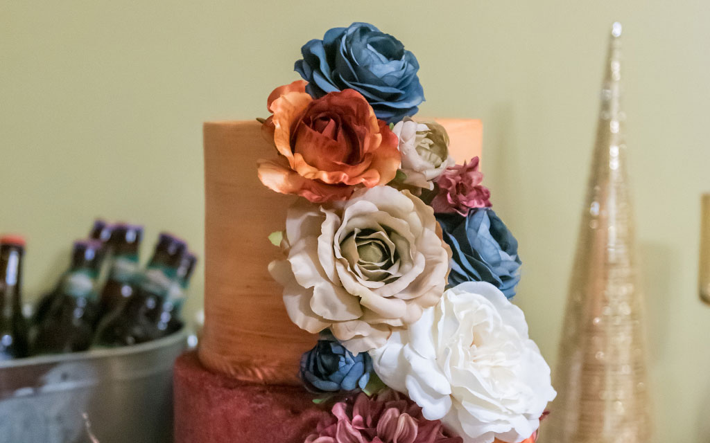 Fall wedding cake with textured buttercream in burgundy and rust, decorated with sugar flowers in jewel tones