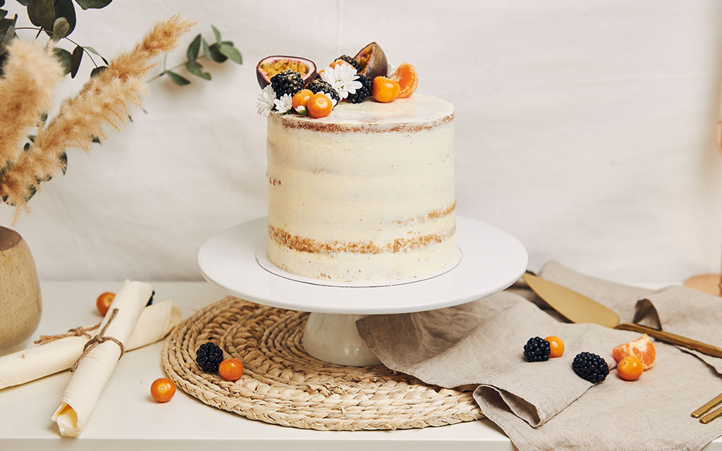 Semi-naked fall wedding cake with fresh figs, blackberries, physalis, and dried pampas grass on white stand