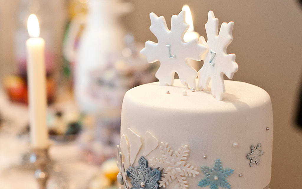 White winter wedding cake with snowflake topper and blue icy snowflake decorations
