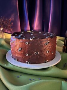 Eyeball Cake in chocolate frosting with candy eyeballs on a green Halloween table, Mia's Bakery