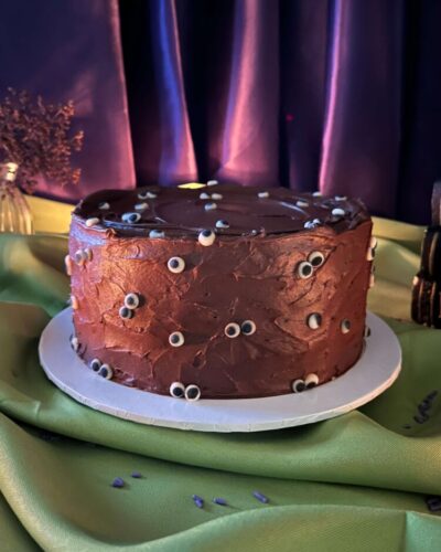 Eyeball Cake in chocolate frosting with candy eyeballs on a green Halloween table, Mia's Bakery