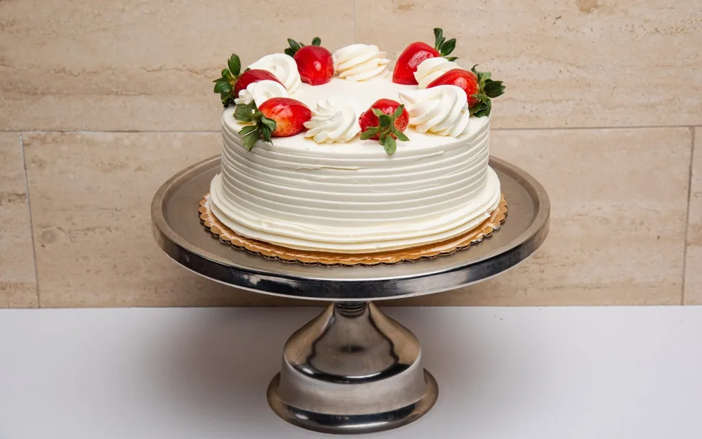 Strawberry shortcake by Mia's Brooklyn Bakery, finished with whipped cream rosettes and fresh strawberries, our best-selling cake